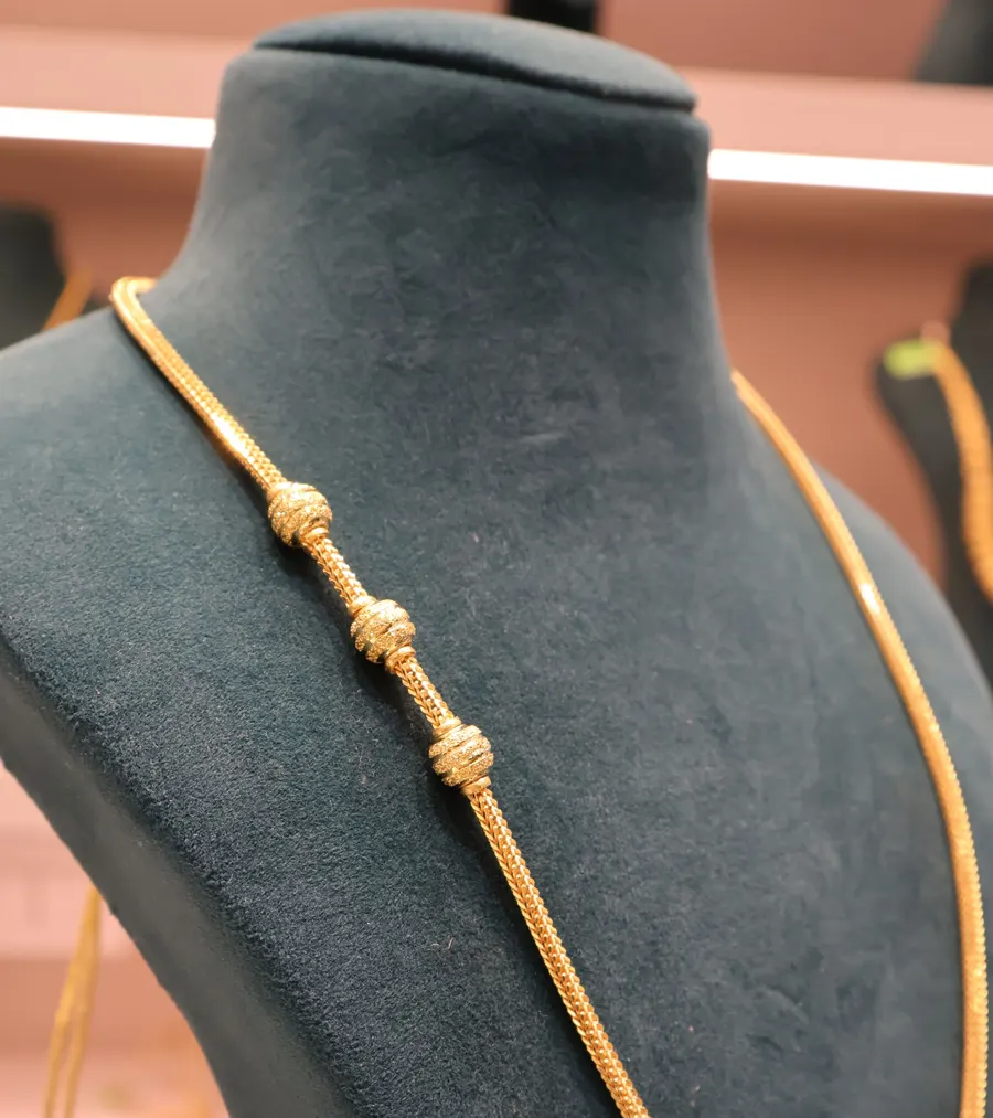 A long gold chain with bead stations on a bust