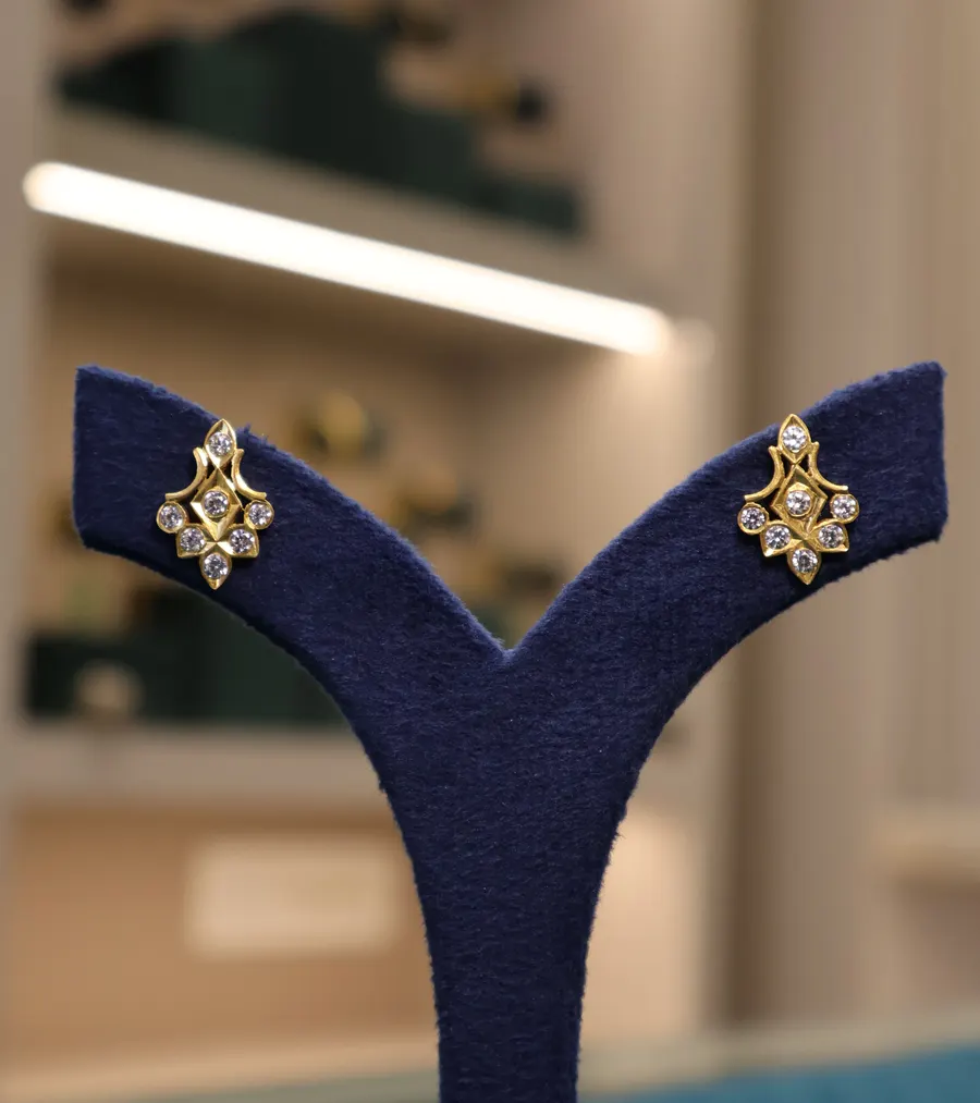 Stone-set gold studs on a navy stand