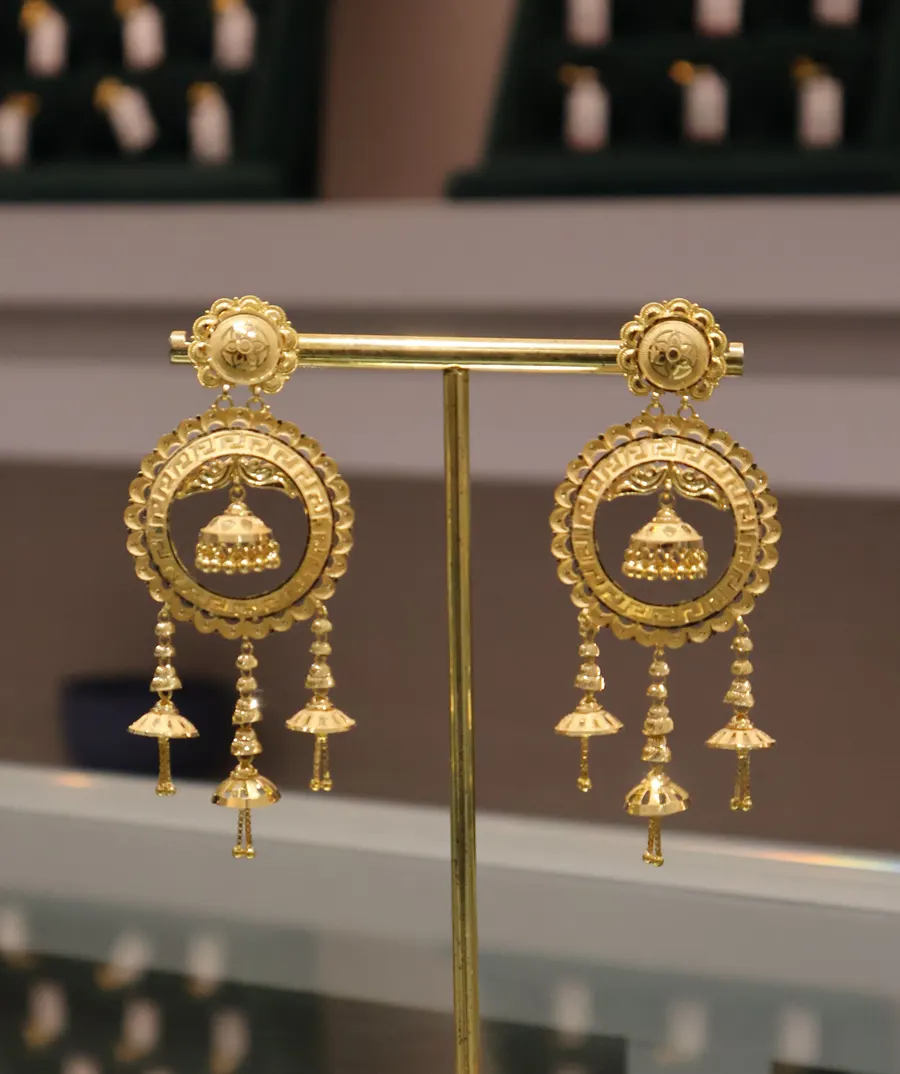 Round 22K jhumka earrings with bell drops on a display stand