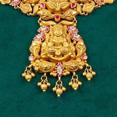 Close-up: Lakshmi seated on the necklace pendant, gold bead drops below