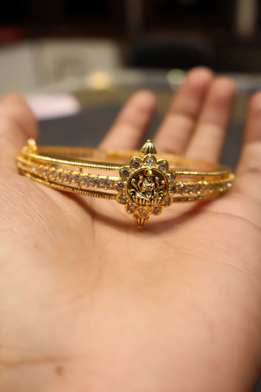 A slim gold bracelet resting on an open palm