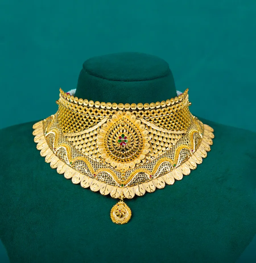 A wide gold choker with a medallion and a single drop