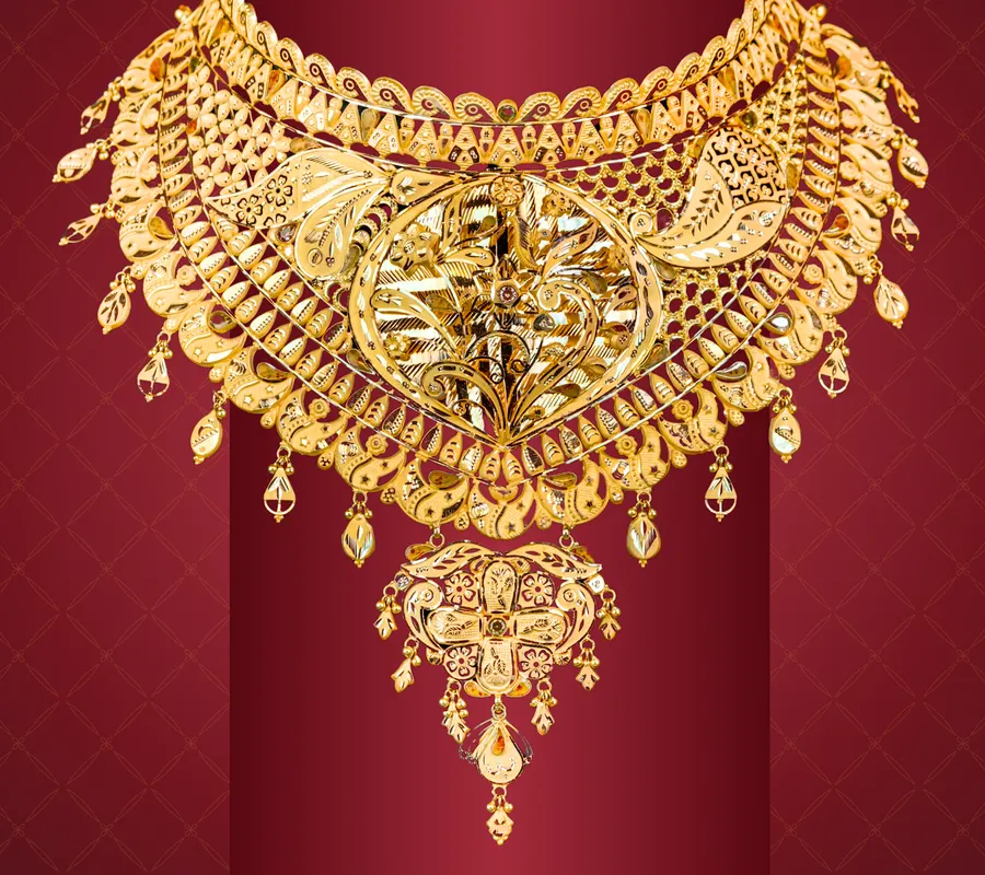 A broad gold necklace with a pendant and bead drops, on maroon