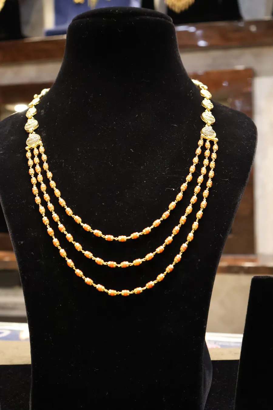 A three-strand gold chain on a black bust