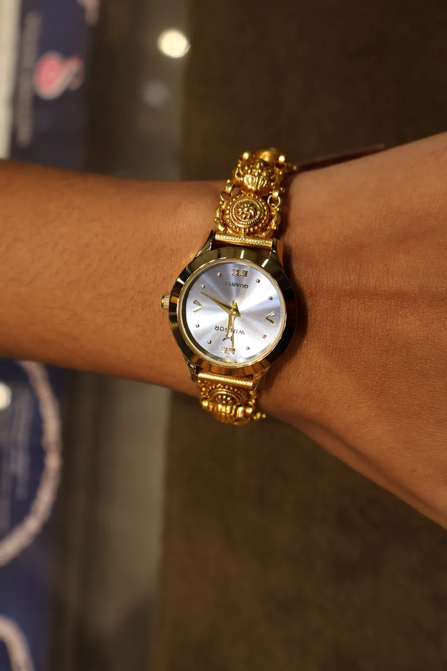 A gold watch worn on a wrist